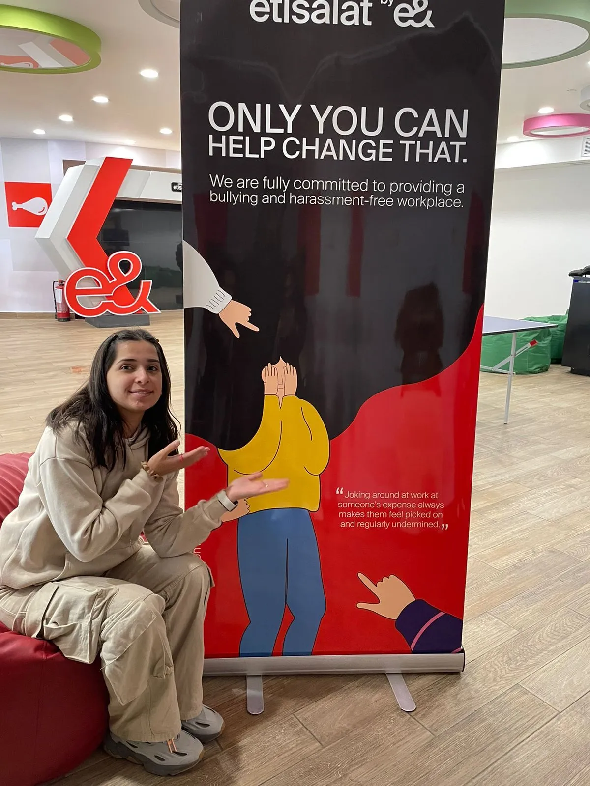Employee posing with evolv e& campaign roll-up banner